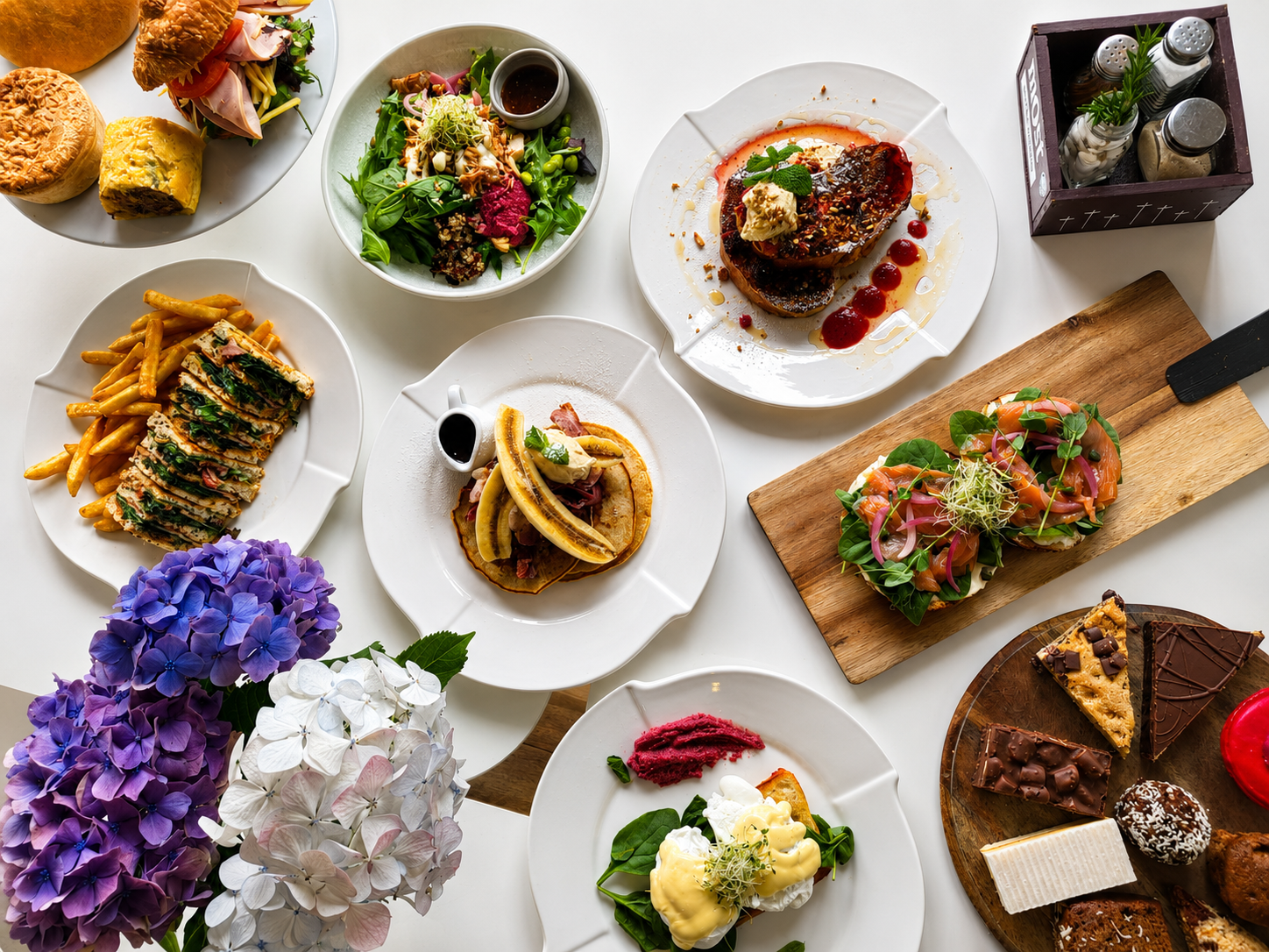 A table spread with brunch dishes, baking and flowers at Gatehouse Cafe